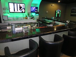 A bar area with a counter, stools, and multiple screens displaying content.