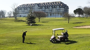 A golf course with a large building in the background.