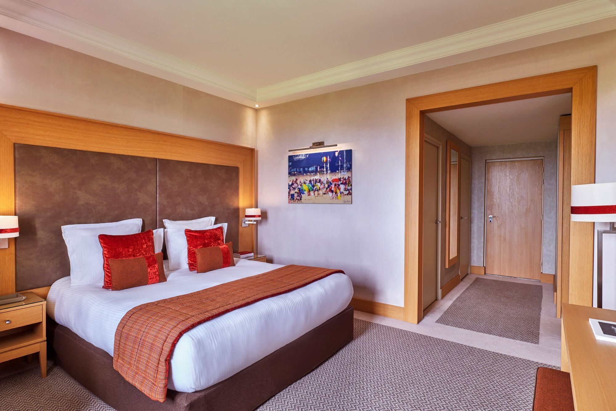 Ein Hotelzimmer mit einem großen Bett, zwei Nachttischen, einer Wandlampe und einem Gemälde.