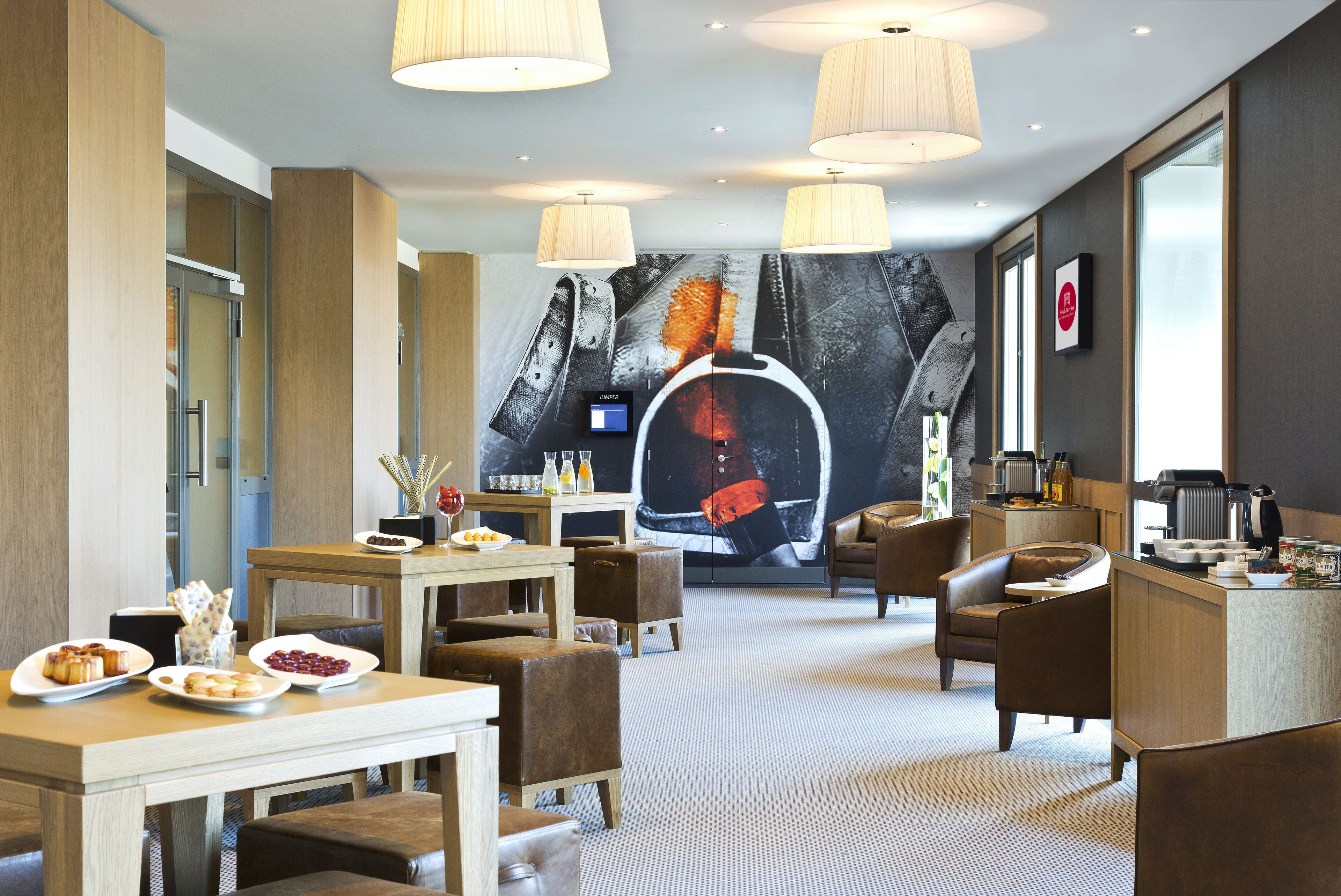 Un vestíbulo moderno de hotel con comedor, asientos, un mural grande y una recepción.