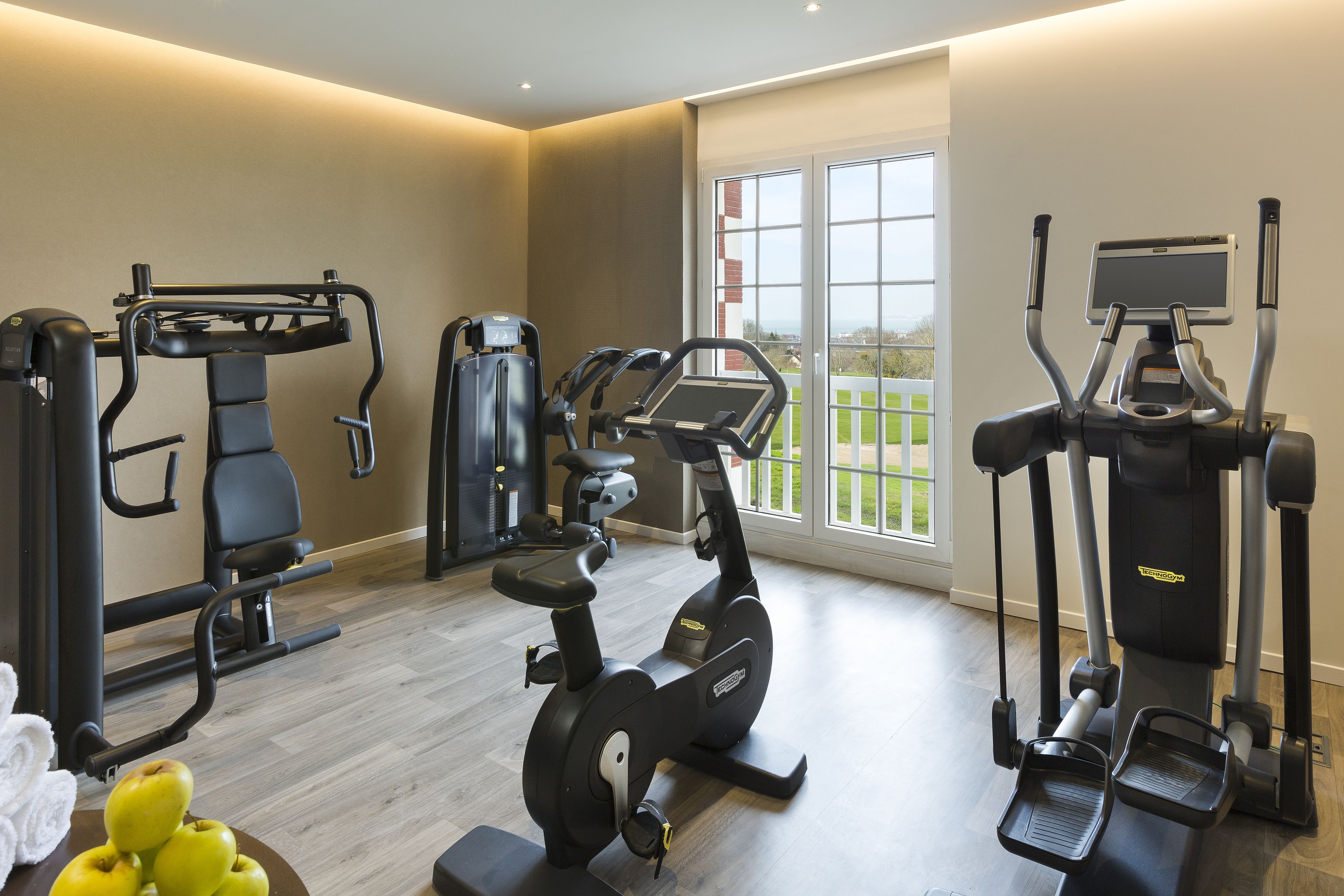 Un gimnasio en casa con diversos equipos de ejercicio, incluyendo una cinta de correr, una elíptica y una máquina de pesas.