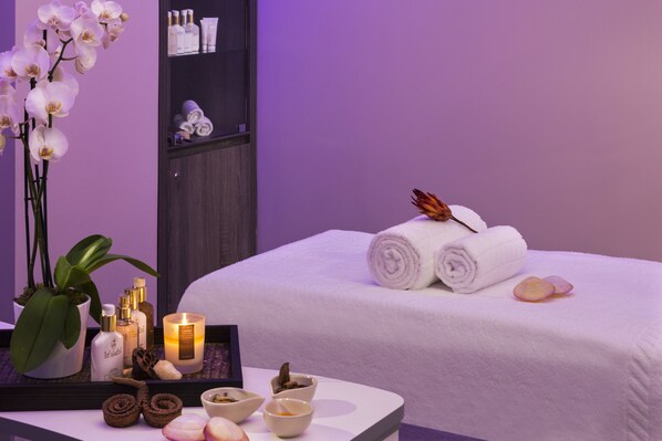 A neatly arranged spa room with a bed, towels, candles, and various spa products on a tray. - Hôtel Barrière L'Hôtel du Golf Deauville (Saint-Arnoult)