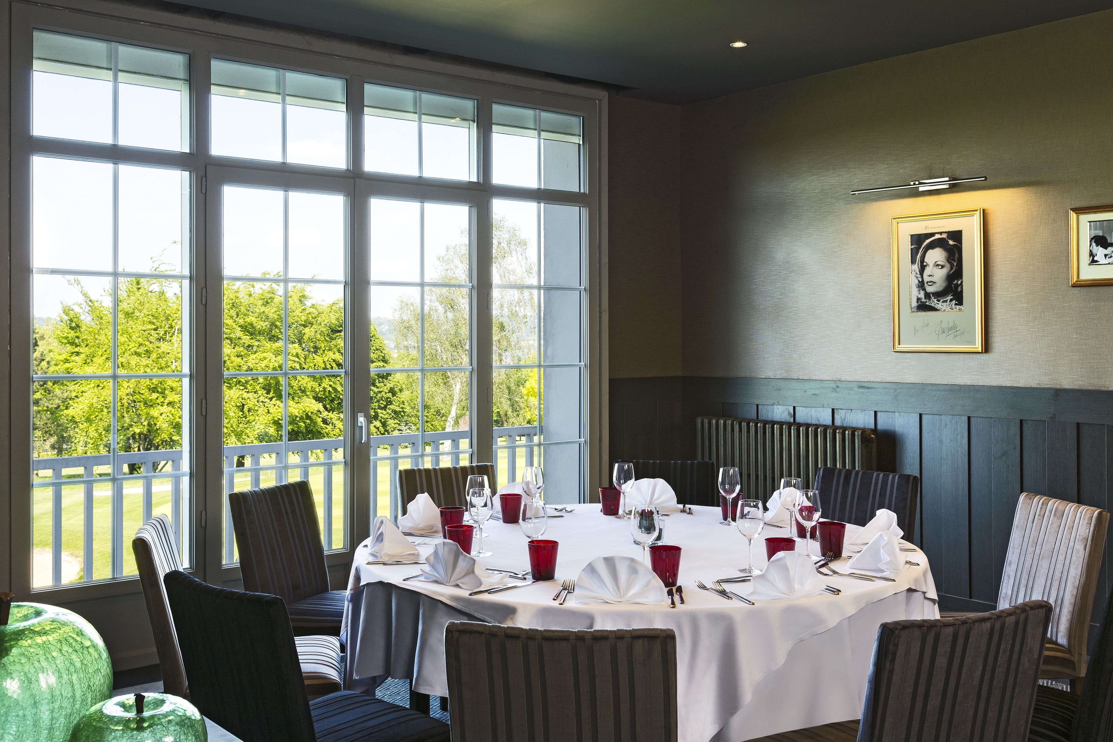 A dining area with a round table set for four, chairs, and a view of greenery outside.