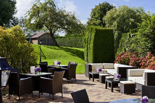 An outdoor patio with wicker furniture, a table, and a lamp.