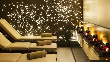 Relax in a serene spa area with reclining chairs, a decorative light installation, and a warm glow.