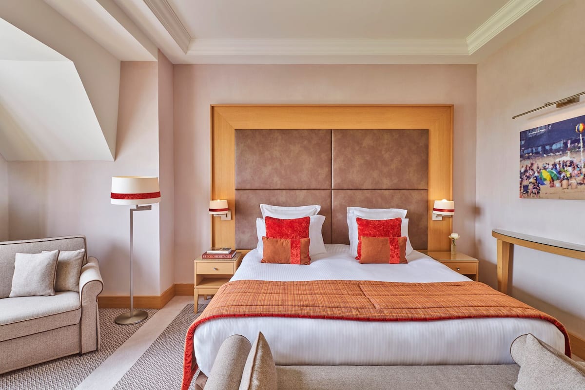 Ein Hotelzimmer mit einem großen Bett, zwei Nachttischen, einem Sofa und einer Stehlampe.