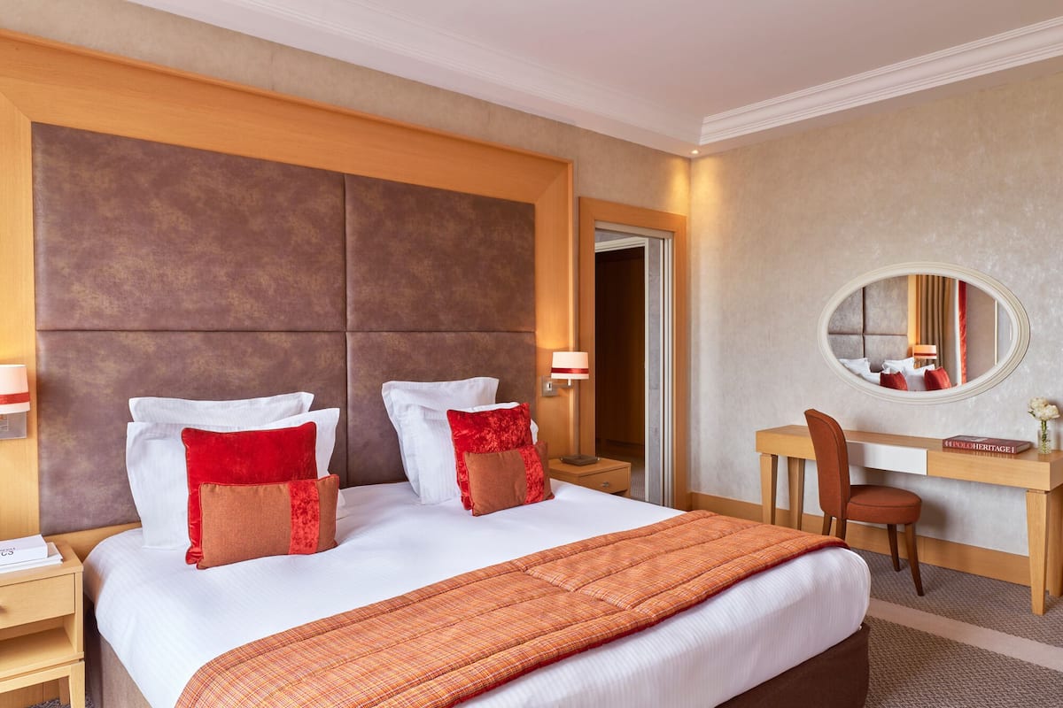 Ein Hotelzimmer mit einem großen Bett, einem Schreibtisch, einem Stuhl, einem Spiegel und einem Nachttisch.