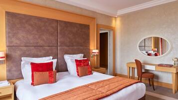 Une chambre d’hôtel avec un grand lit, un bureau, une chaise, un miroir et une table de chevet.