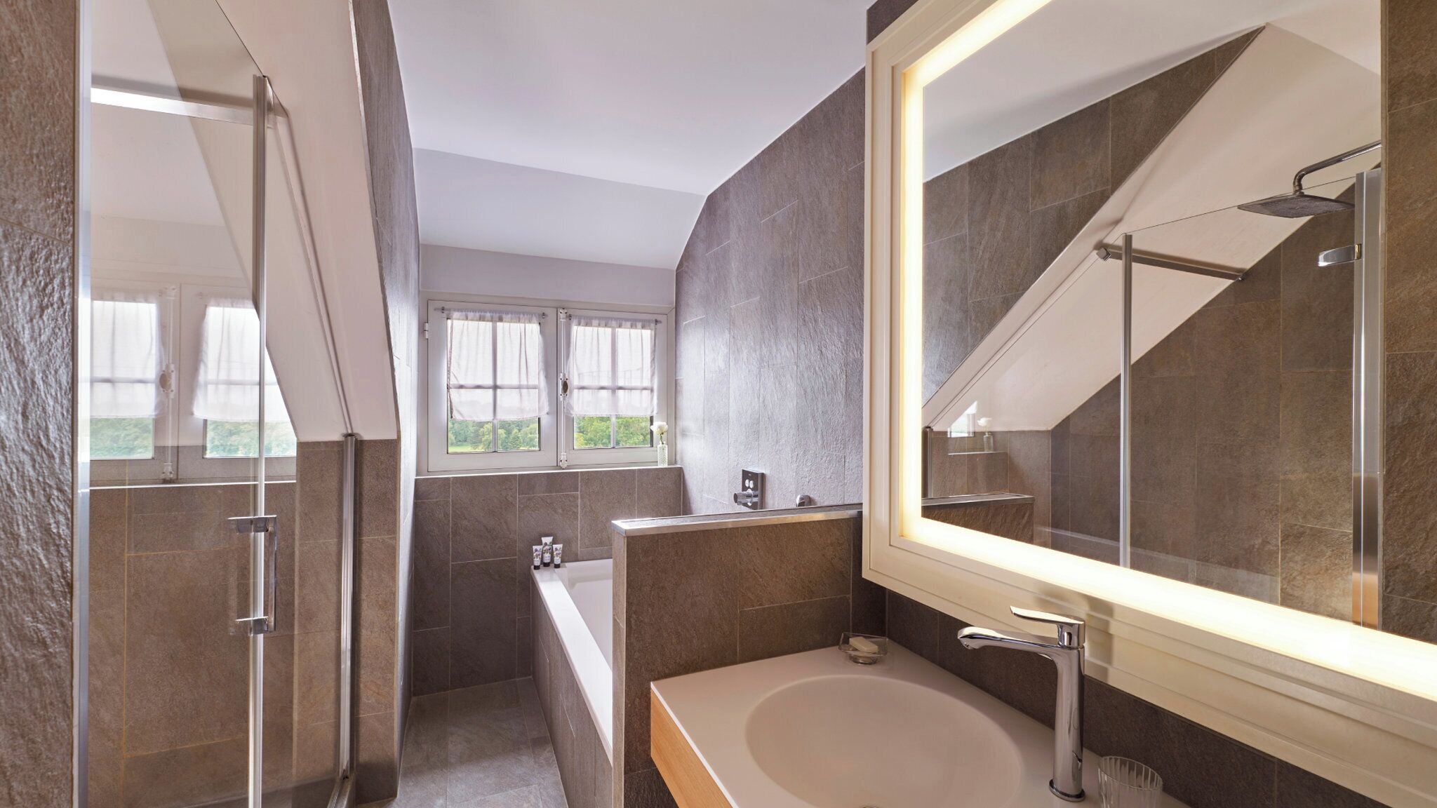 Une salle de bain moderne avec un grand miroir, une baignoire et un espace douche.