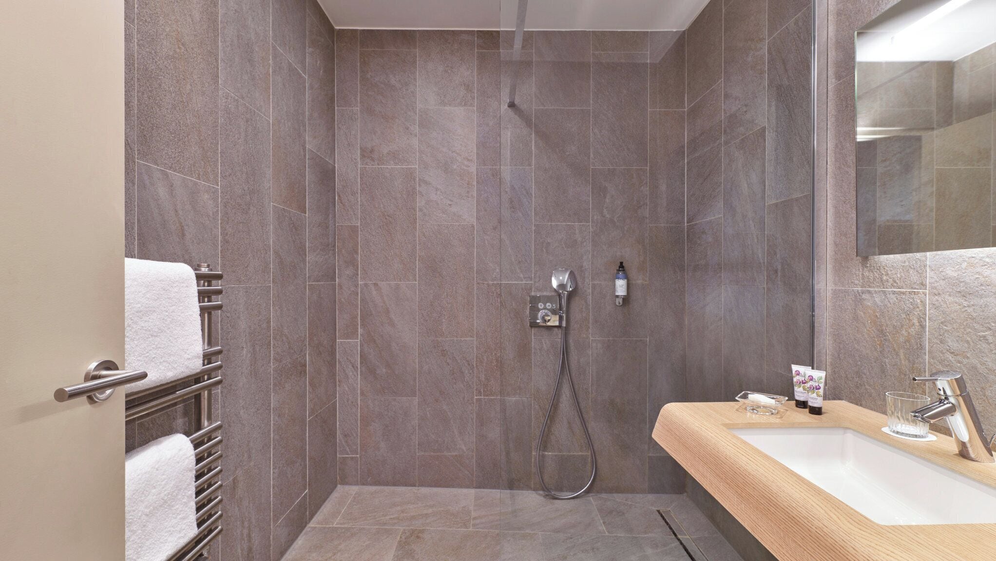 A modern bathroom with a shower, a sink, and a towel rack.