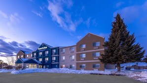 A multi-story hotel with a prominent sign, a parking lot, and a snow-covered landscape.