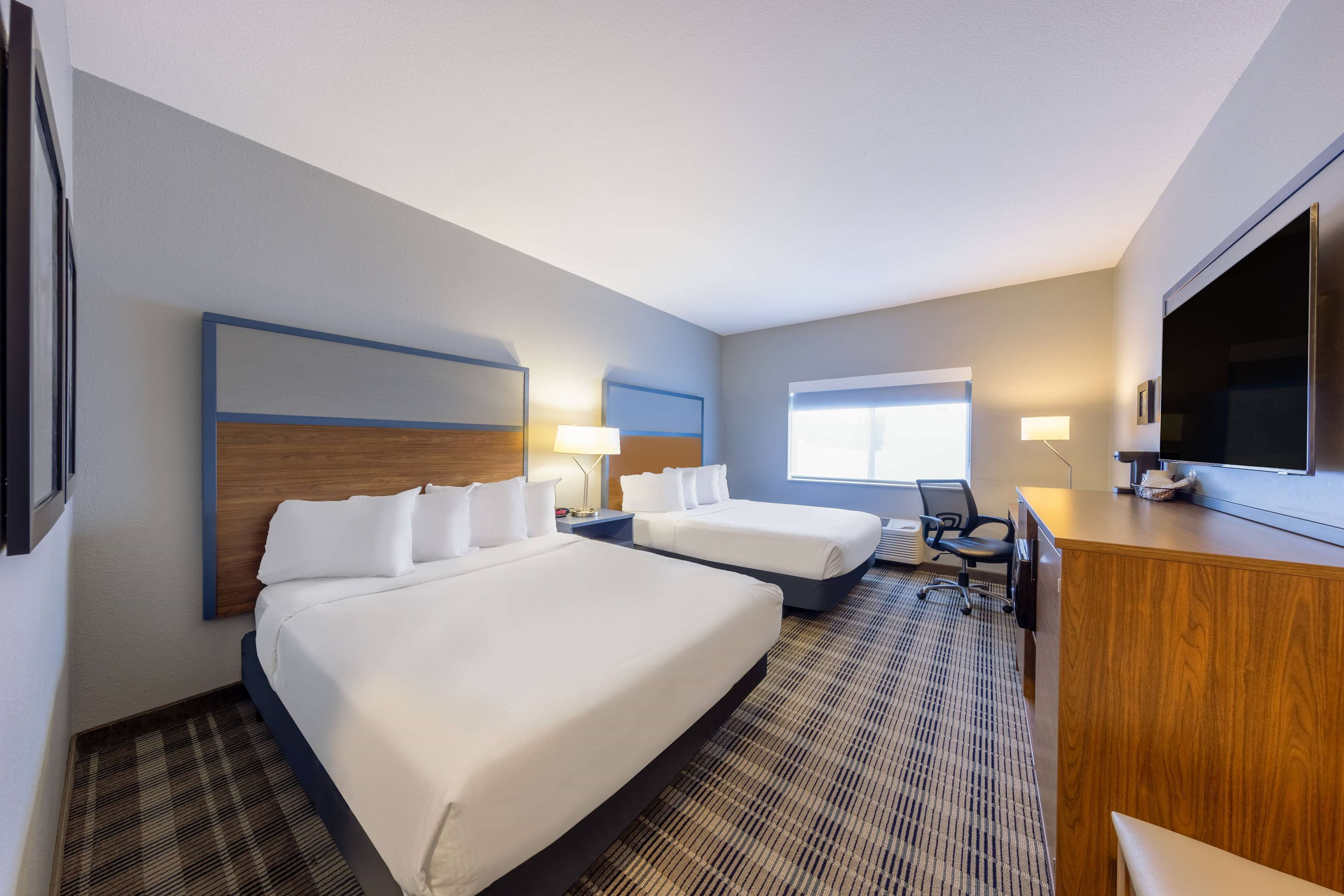 Une chambre d’hôtel avec deux lits, un bureau, une télévision et une fenêtre.