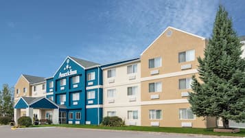 Stunning hotel building with a flat roof and symmetrical windows, set amidst a beautifully manicured lawn and trees.