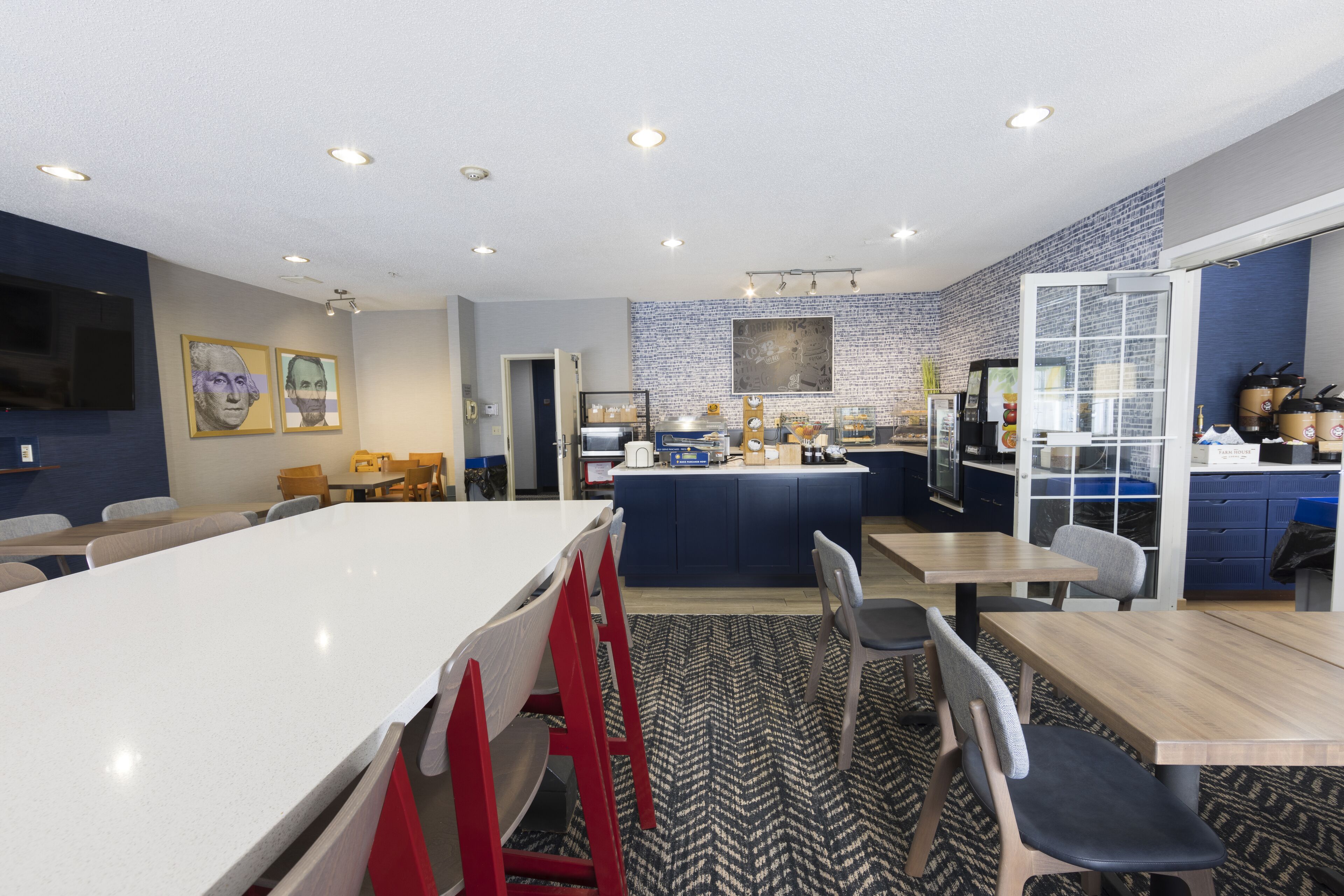Une cuisine moderne dotée d’un îlot central, de tabourets de bar et d’un coin repas avec des tables et des chaises.