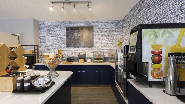 A modern kitchen with a coffee station, a chalkboard menu, and a juice dispenser.