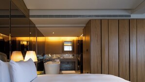 A hotel room with a large bed, a bathroom with a sink and mirror, and a wooden wardrobe. - The Landis Taipei (Taipei)