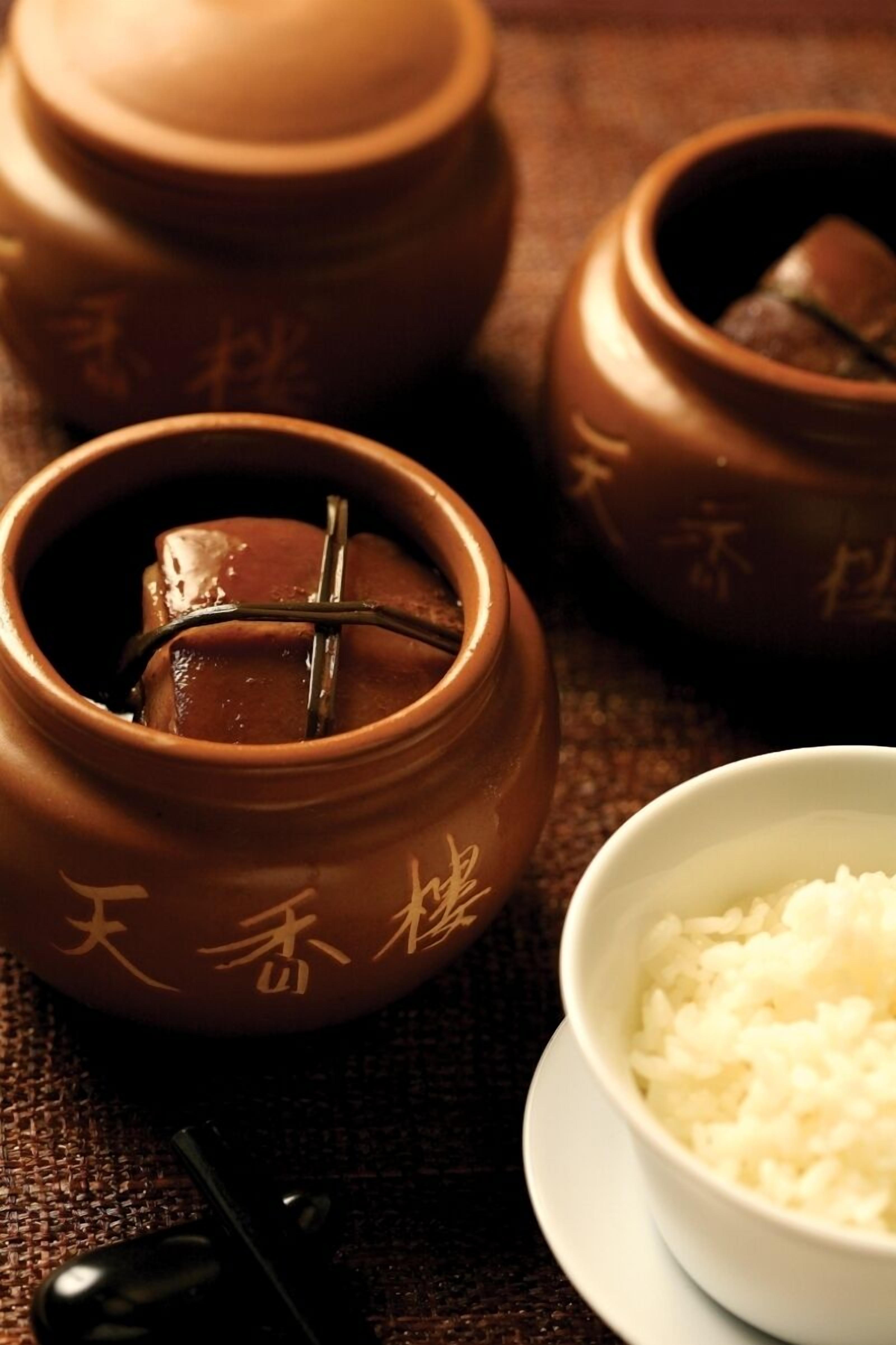 A traditional tea set with a teapot and cups, accompanied by a bowl of rice.