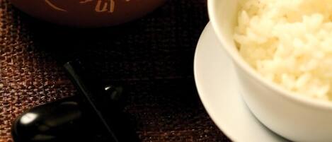 A traditional tea set with a teapot and cups, accompanied by a bowl of rice.