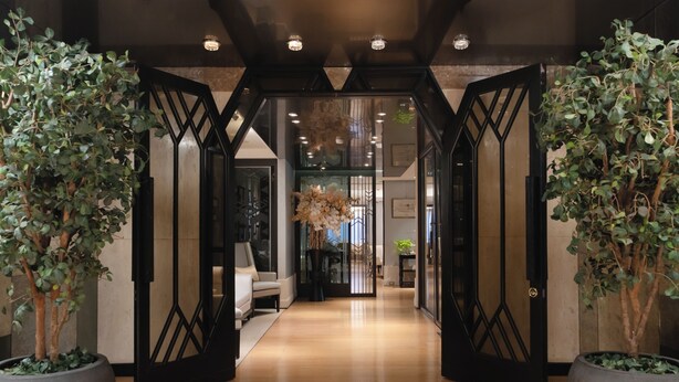 A hallway with a modern design, featuring a geometric black gate, potted plants, and a light-colored floor. - The Landis Taipei (Taipei)