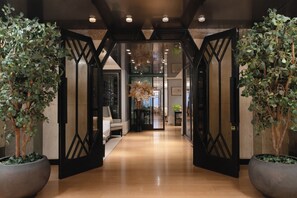 A hallway with a modern design, featuring a geometric black gate, potted plants, and a light-colored floor. - The Landis Taipei (Taipei)