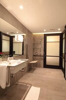 Un baño moderno con un espejo grande, un lavamanos y una zona de ducha.