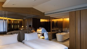 A modern hotel room with two large beds, a sitting area, a large mirror, a bathtub, and a vanity with a sink. - The Landis Taipei (Taipei)