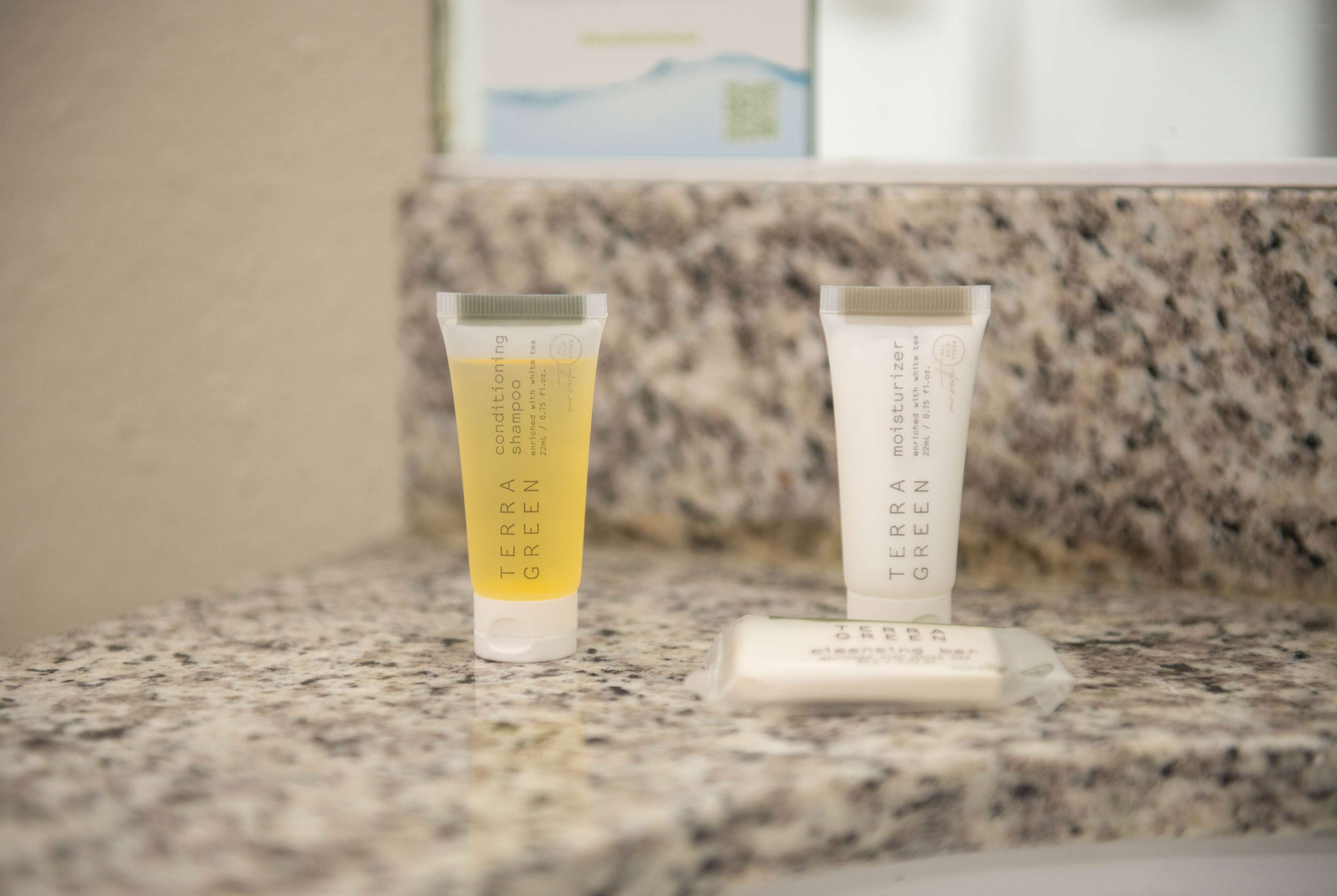 Two tubes of Terra Green shampoo and conditioner on a granite countertop.