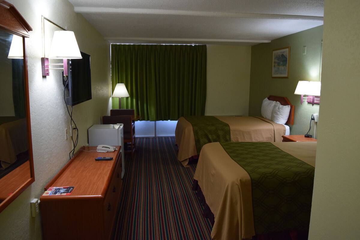 A hotel room with two beds, a desk, a telephone, and a television.