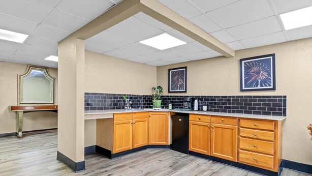 A modern kitchen with wooden cabinets, a black backsplash, and a dishwasher.