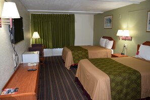 A hotel room with two beds, a desk, a chair, a TV, and two lamps.