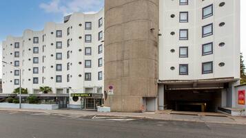 Un hotel moderno con una torre central cilíndrica distintiva, varios pisos y la entrada a un estacionamiento.