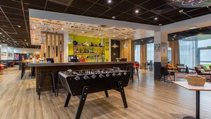 A bar area with a foosball table, seating, and a bar counter with a variety of bottles. - B&B Hotel Orléans Centre Foch (Orléans)