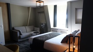 Una camera d'albergo moderna con un letto, un divano, un tavolino e una ventola.