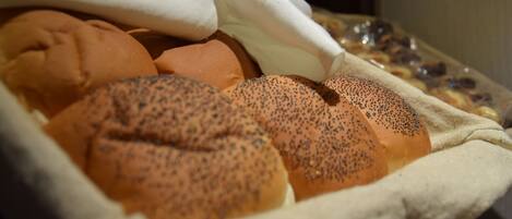 A basket of various baked goods, including poppy-seeded rolls and other pastries.