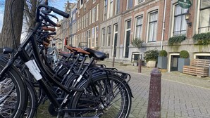 Una fila di biciclette parcheggiate su una strada acciottolata di fronte a un edificio storico con un cartello che indica 'PRINSENGRACHT HOTEL'.