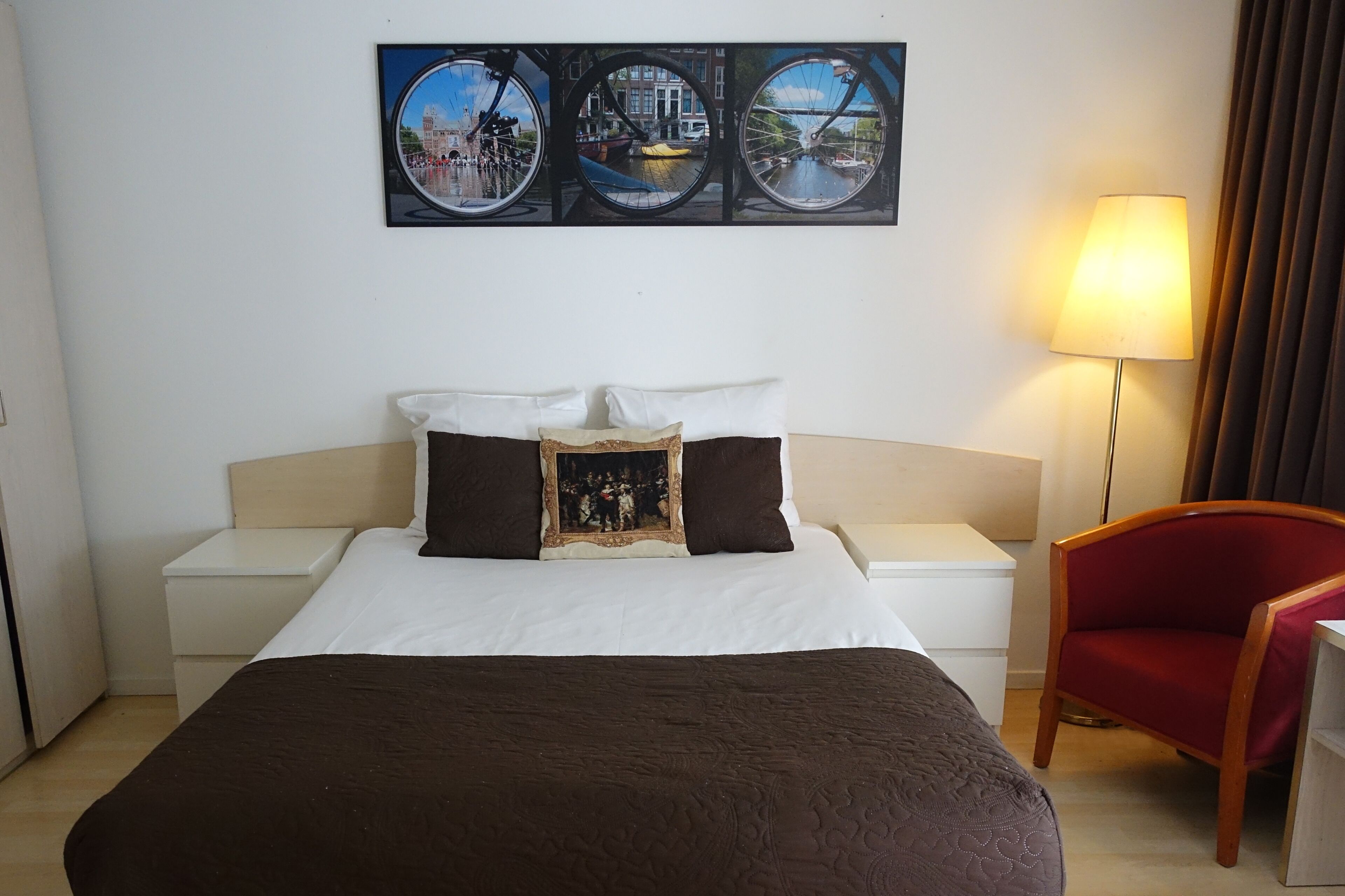 Ein Hotelzimmer mit einem Bett, einem Nachttisch, einer Lampe, einem Sessel und einer Wand mit drei runden Fotos.