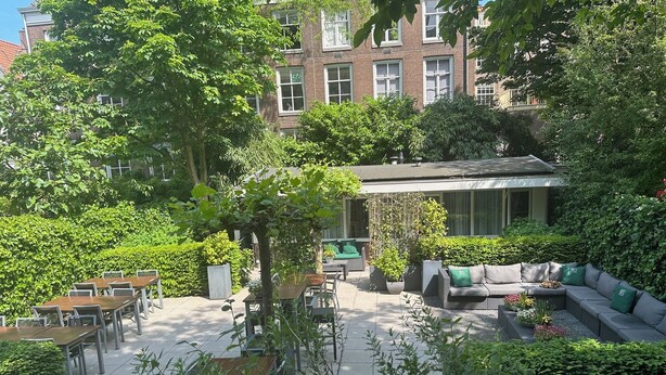 Un cortile con posti a sedere all'aperto, un divano e un pergolato.