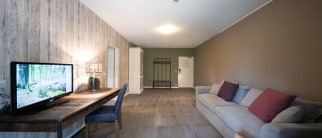 Una sala de estar moderna con un televisor de pantalla plana, una mesa de comedor de madera, un sofá y un sillón de cuero.
