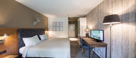 Una habitación de hotel moderna con una cama grande, un escritorio con ordenador, asientos de cuero y una decoración de cabeza de ciervo.