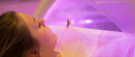 A person lying down in a room with a purple light.