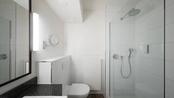 A modern bathroom with a glass shower enclosure, a white toilet, and a granite countertop.