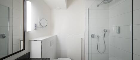 A modern bathroom with a glass shower enclosure, a white toilet, and a granite countertop.