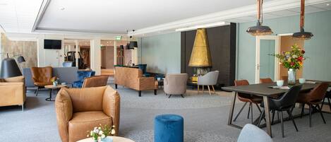 Un hall amplio con mobiliario moderno, chimenea y comedor.