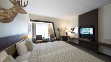 Habitación de hotel con una cama grande, una cabeza de ciervo montada en la pared, un televisor, un escritorio y una silla.