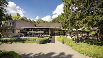 Traditional architecture meets serene surroundings in this picturesque setting, offering a central entrance and outdoor seating areas.