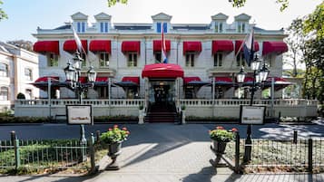 Stately building with a classic facade, featuring a central entrance and a flagpole, surrounded by a paved walkway and ornate details.