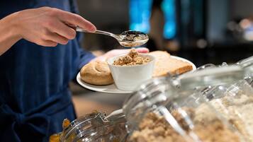 A buffet with various food items and a person serving themselves.