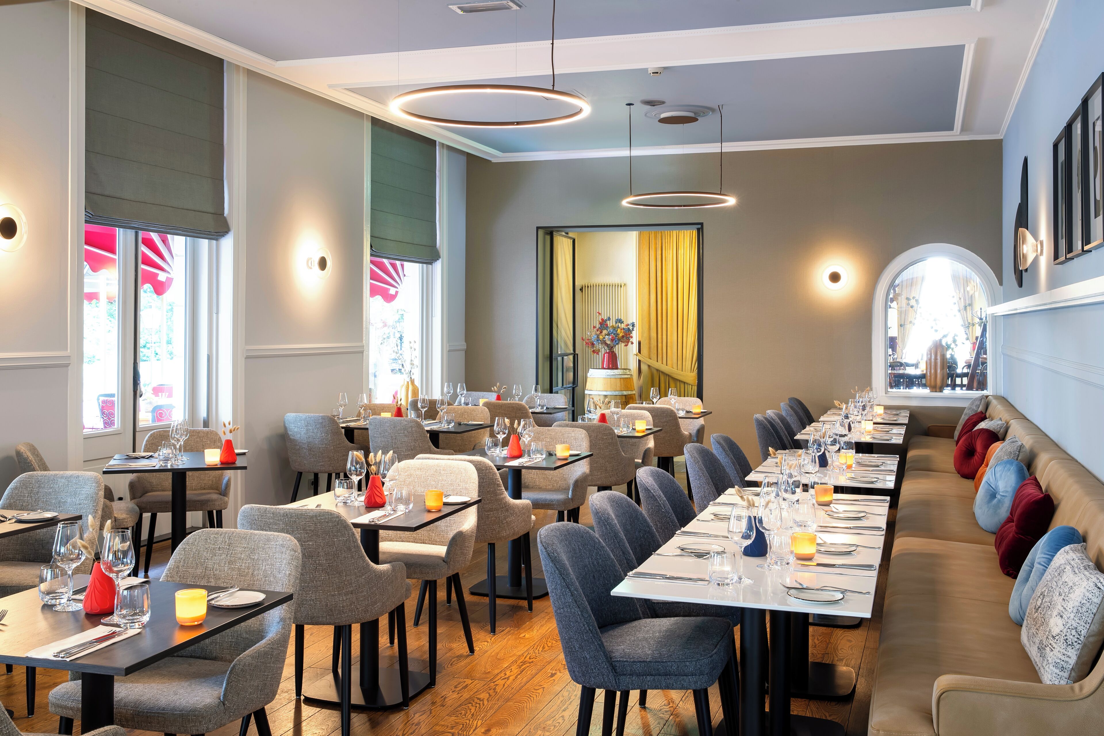 A restaurant with long tables, chairs, and a sofa.