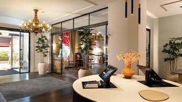 A reception area with a digital kiosk, potted plants, and a chandelier.