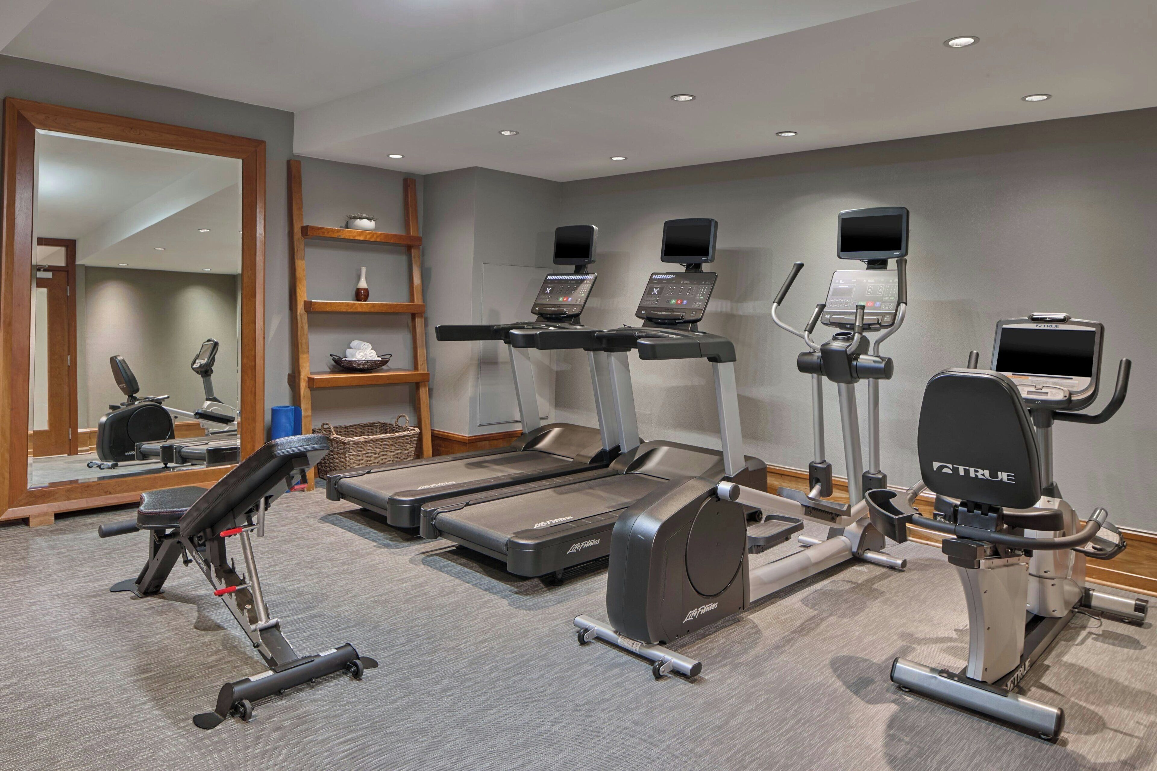 Une salle de sport équipée de tapis de course, de vélos elliptiques et de matériel de musculation.